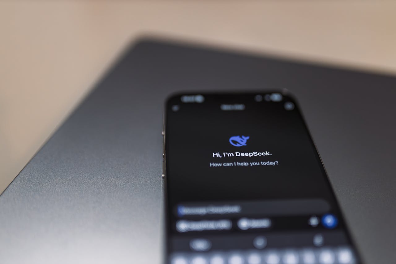 about-us-01 Close-up of a smartphone with AI assistant interface on screen over a laptop.